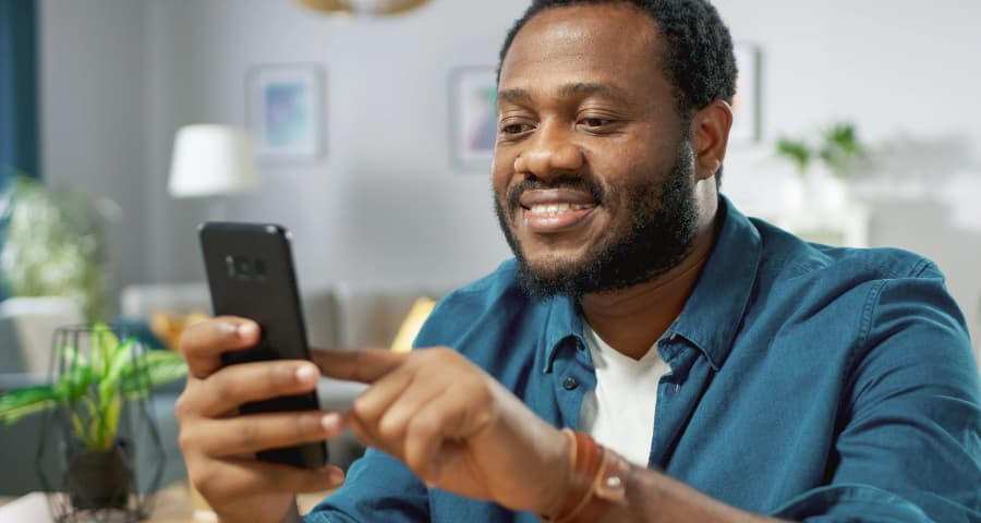 Man at home using a home security app on his smartphone
